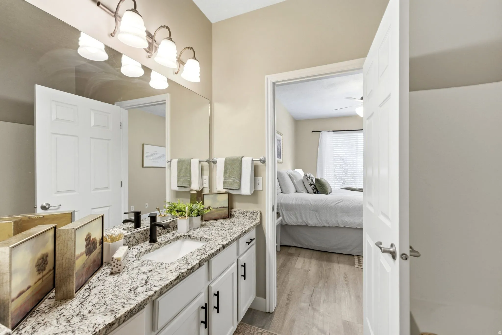 Vanity featuring a stone countertop, dual undermount sinks, and white cabinetry with matte black hardware