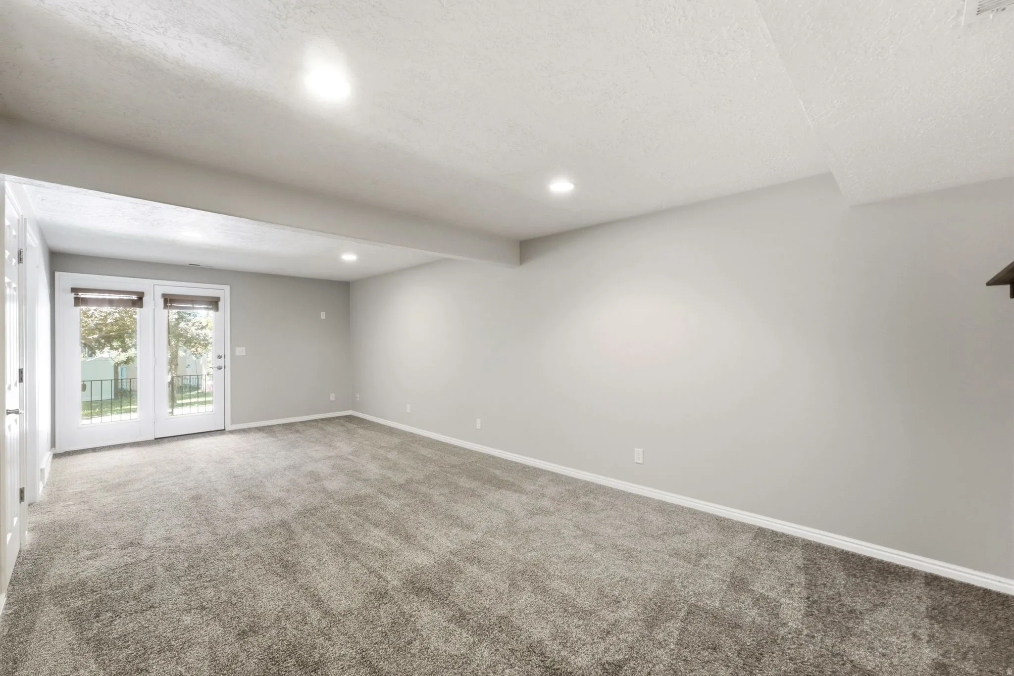 Spacious room with gray textured carpet, recessed lighting, and neutral-toned walls