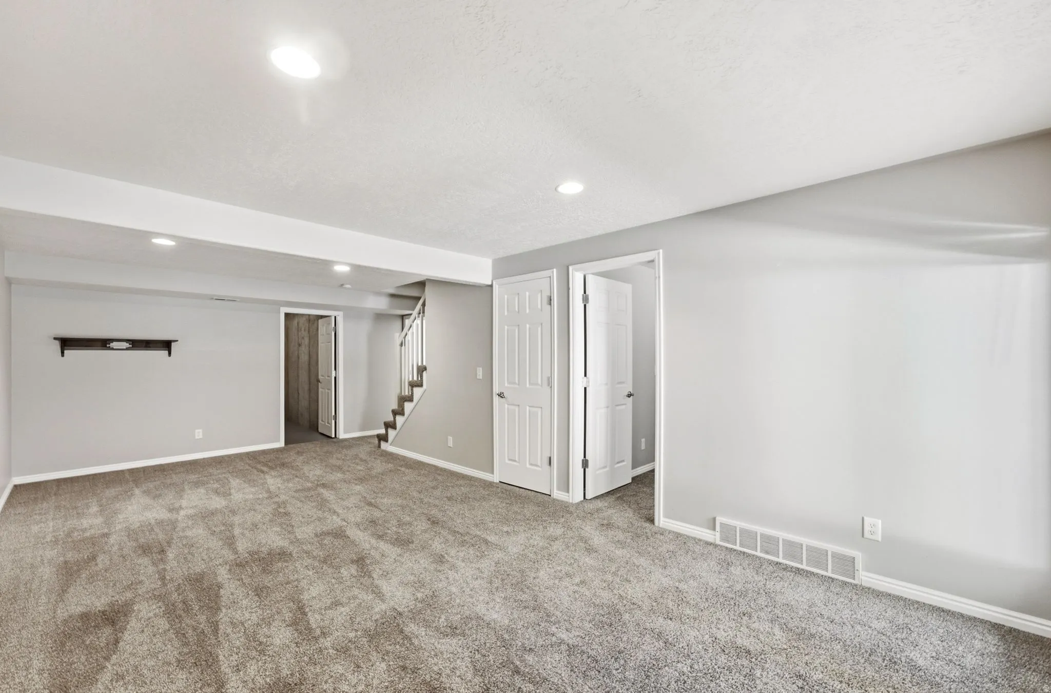 Recessed lighting throughout, neutral-toned carpeting, light gray walls, white trim, and white paneled doors