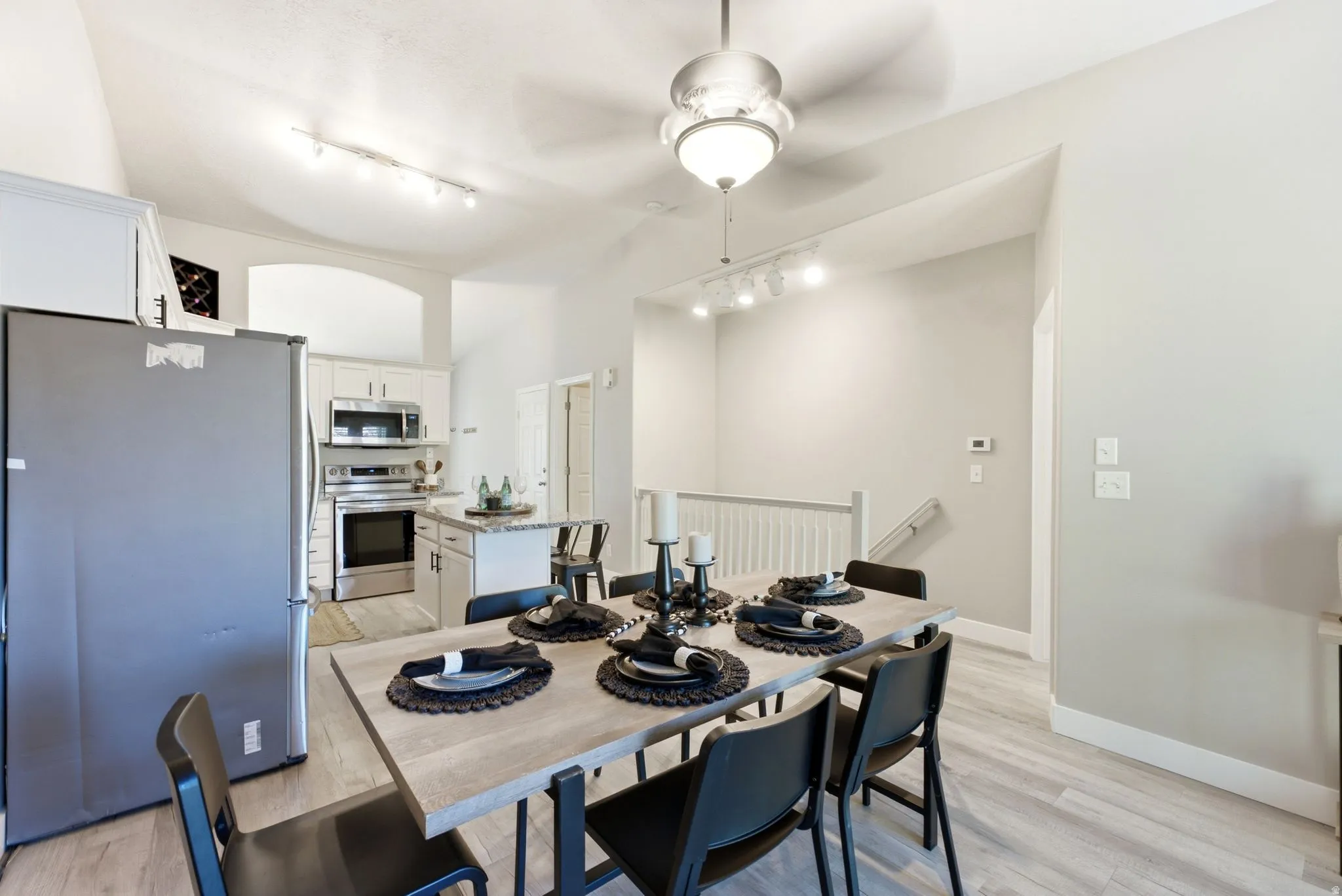 Dining area with wood-finish flooring, a contemporary ceiling fan, and track lighting