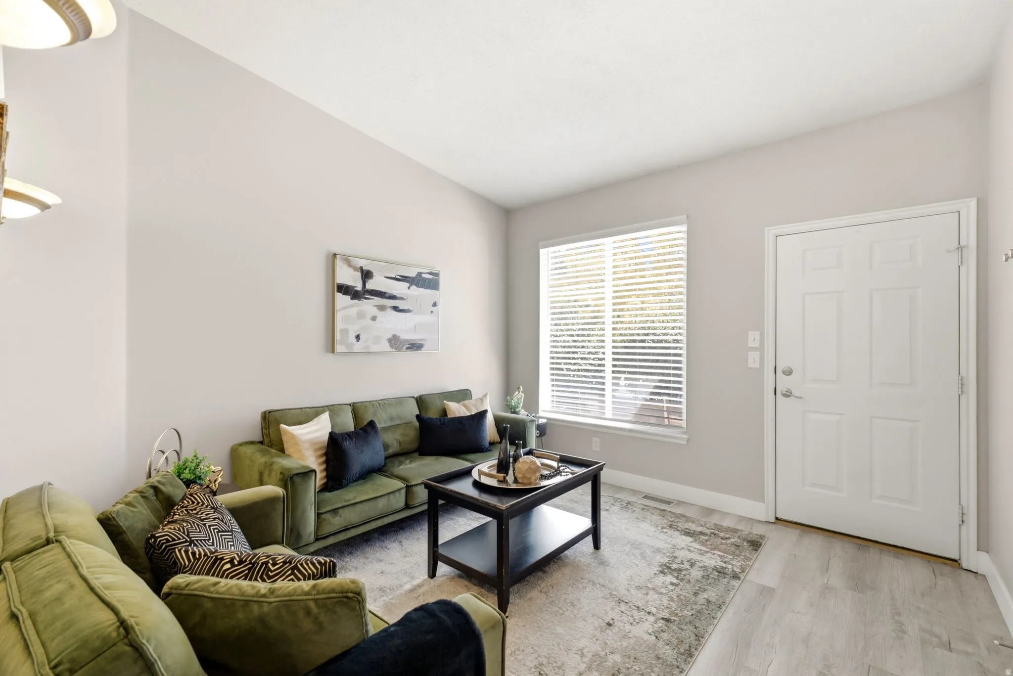 Vaulted ceiling, prominent window, paneled entry door, light wood-finish flooring, and recessed lighting