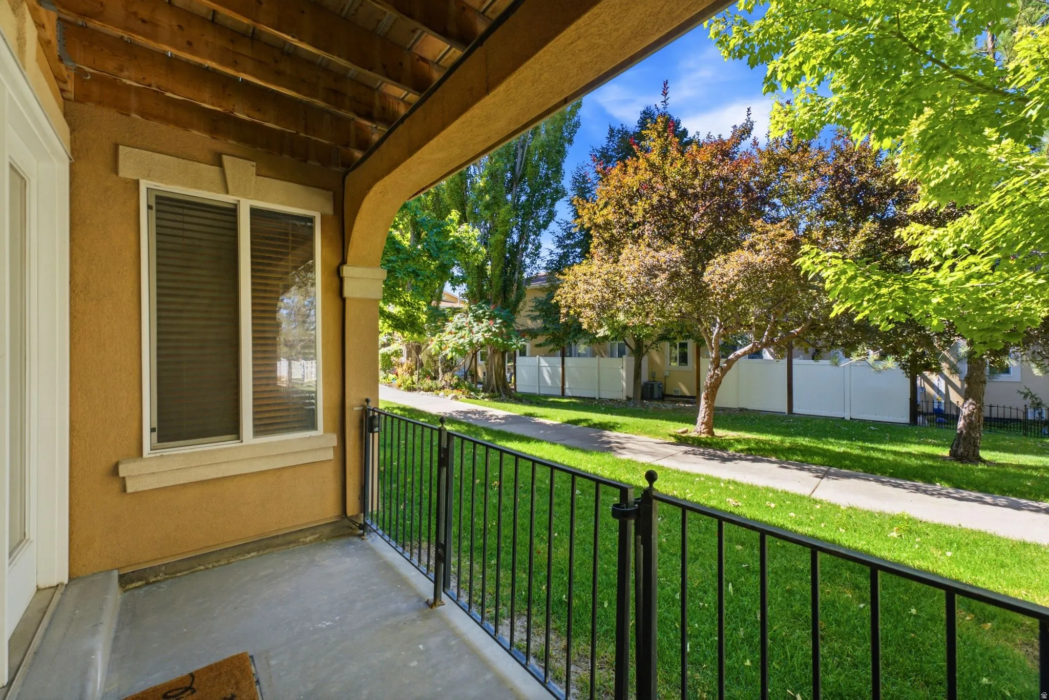 Covered porch with exposed wood ceiling, stucco exterior, decorative window trim, and wrought iron railing