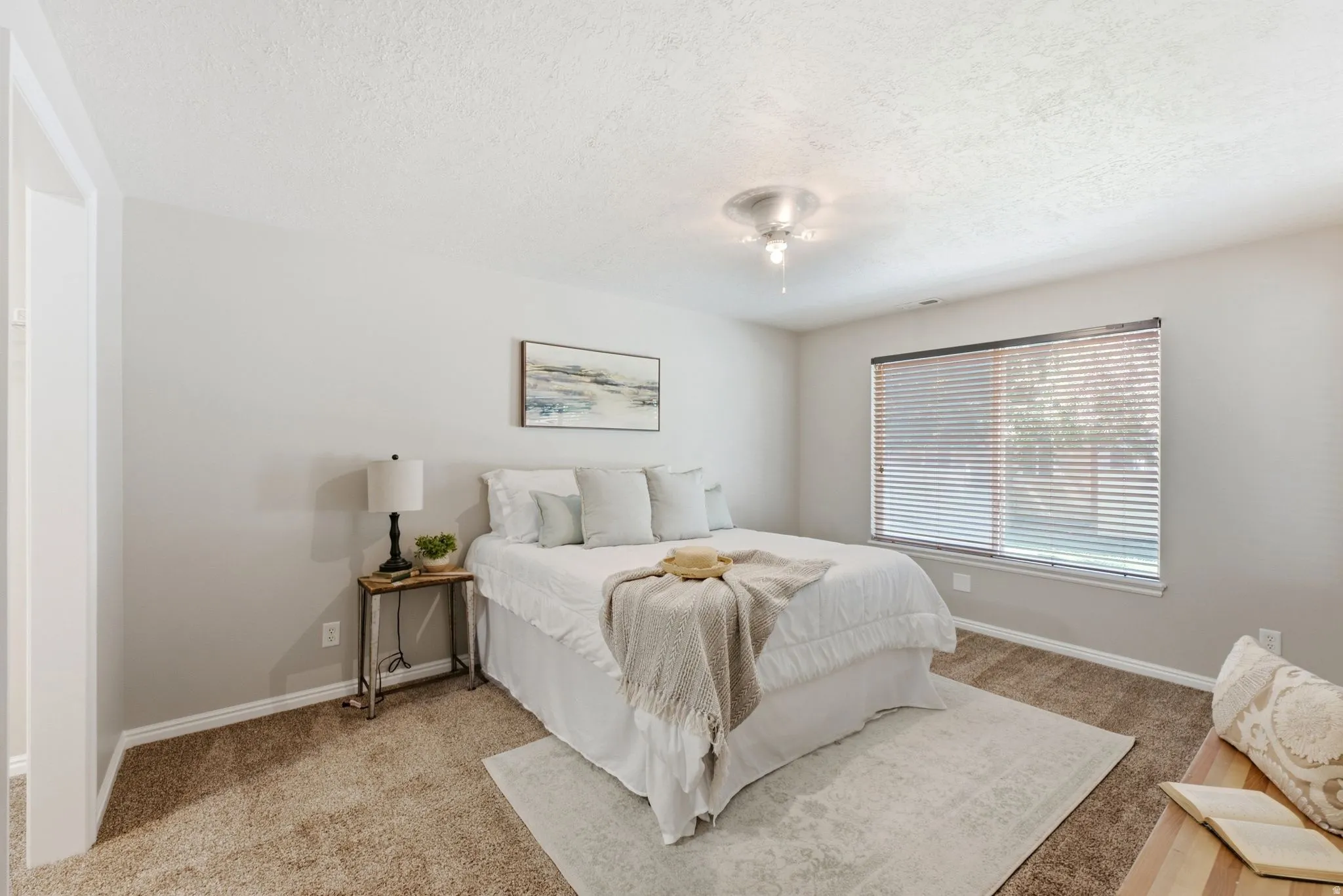 Carpeted flooring with an area rug, a window with blinds, and ceiling-mounted lighting