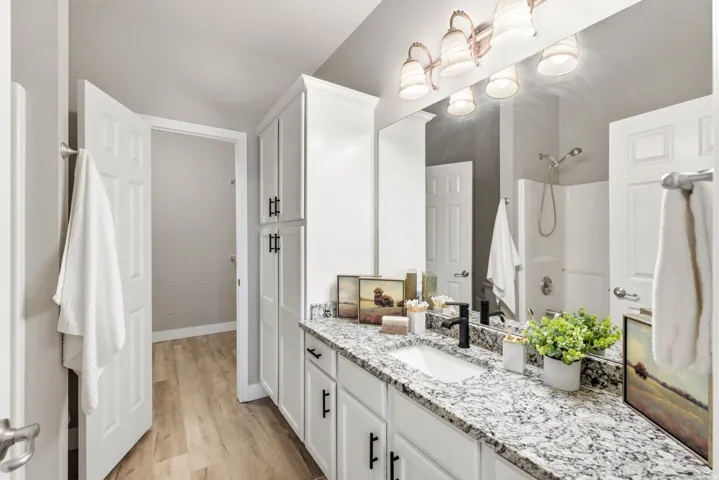 Dual vanity with white cabinetry, speckled countertop, and black fixtures