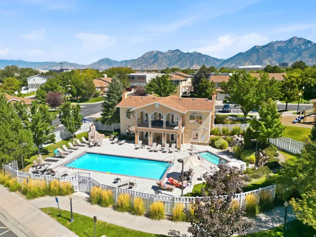 Community pool with surrounding patio, a separate hot tub, fenced perimeter, and nearby playground