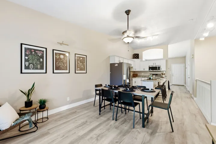 Vaulted ceilings, wood-finish flooring, and a kitchen featuring white cabinetry, stainless steel appliances, and a central island