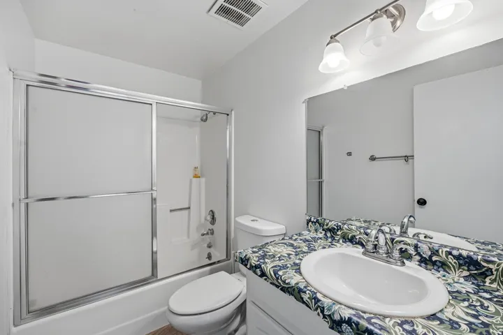 Bathroom featuring a shower/tub combination with sliding glass doors, a vanity with an integrated sink, and an overhead light fixture