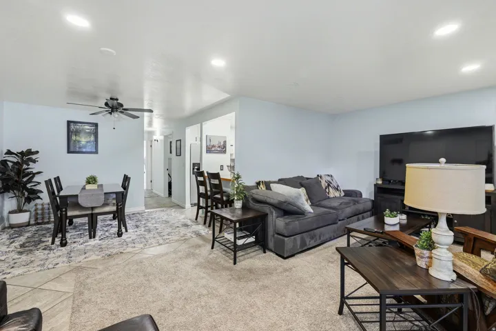 Recessed ceiling lighting, ceiling fan, carpet flooring, wood-finish dining table, and built-in breakfast bar