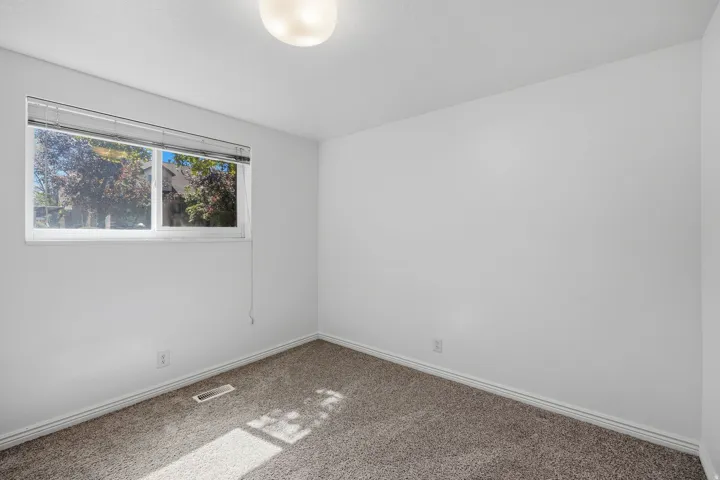 Window with exterior views, neutral wall color, and textured carpet flooring