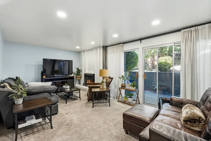 Recessed lighting, brick-clad fireplace, carpeting, and sliding glass doors