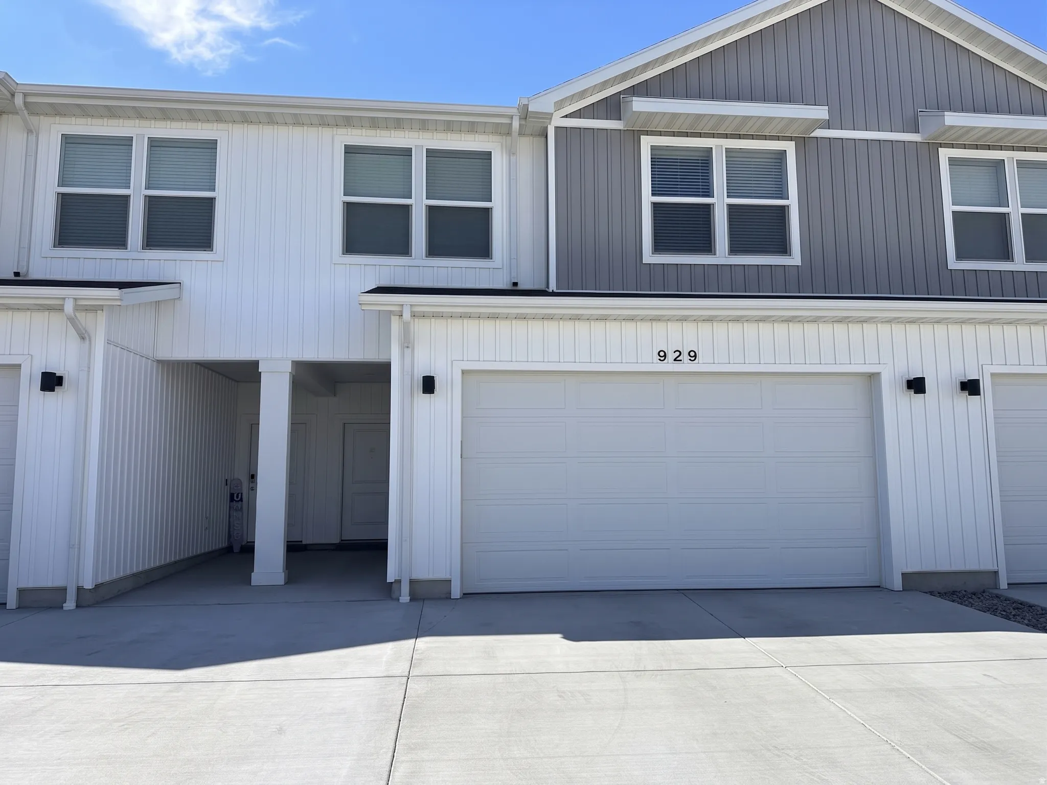 Two-tone vertical siding exterior with integrated garage, covered entry, and black exterior lighting fixtures