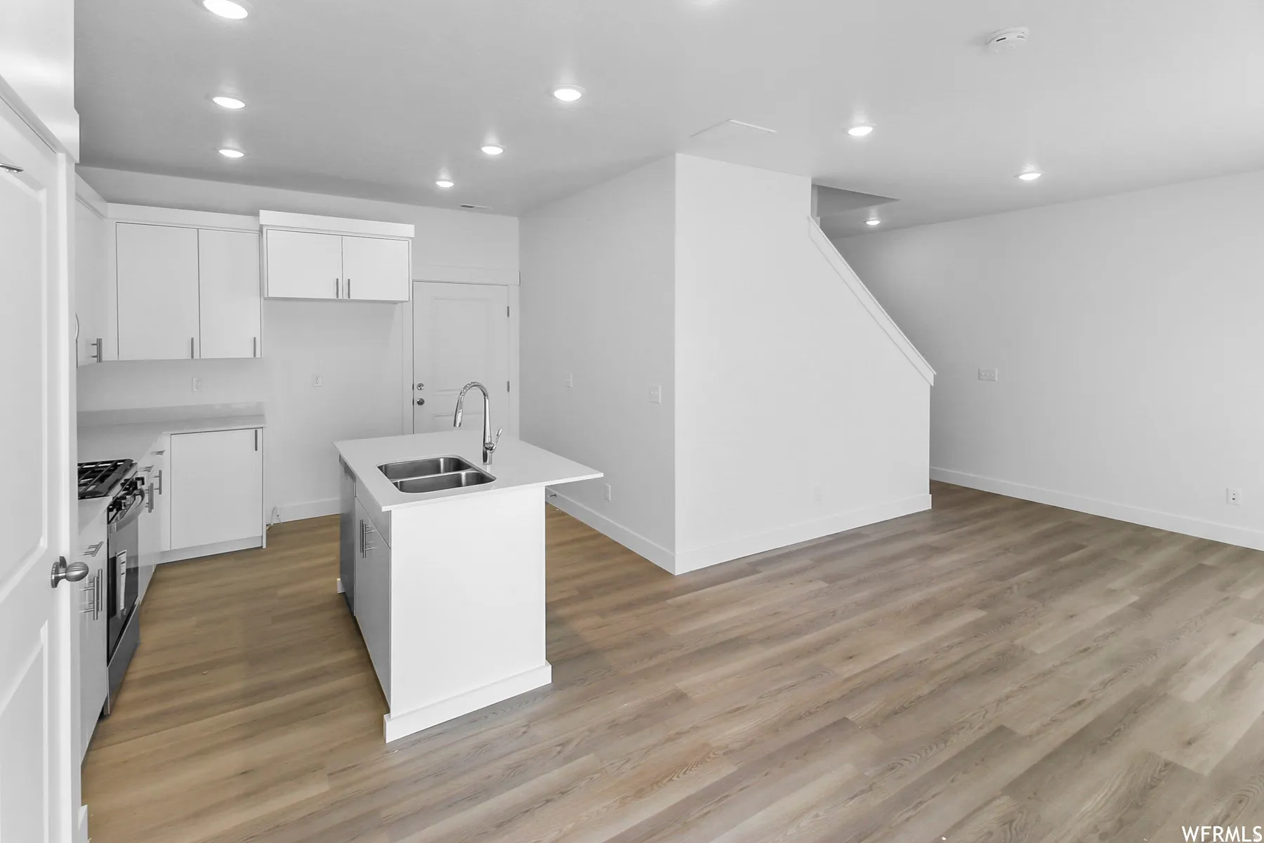 Modern kitchen featuring white cabinetry, a center island with an undermount double-basin stainless steel sink, and stainless steel appliances