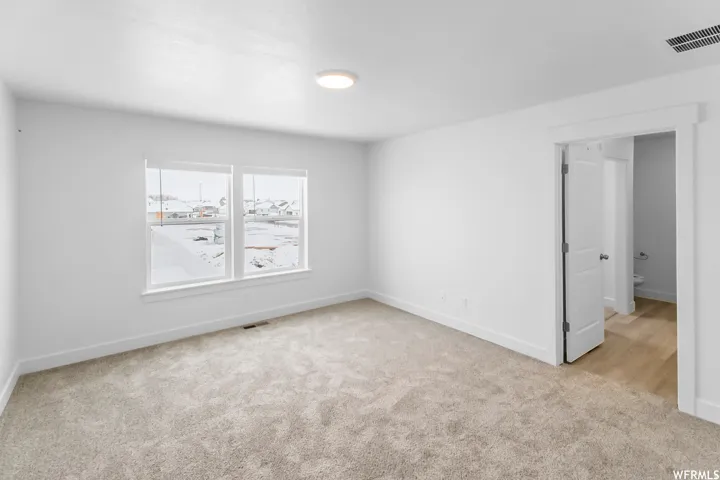 Dual windows with white trim, recessed ceiling light, and light-colored carpeting