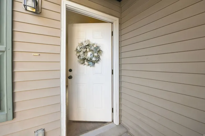 Entry with a white paneled door, exterior wall light fixture, and horizontal siding