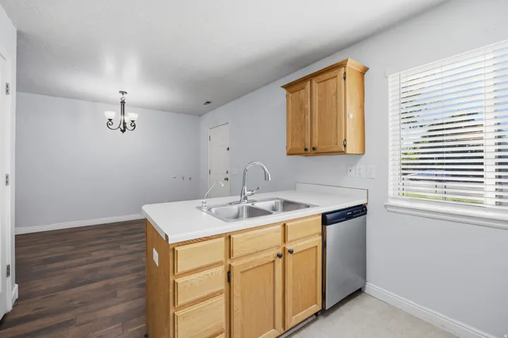 Kitchen island with a double basin stainless steel sink, wood-finish cabinetry, and white countertops