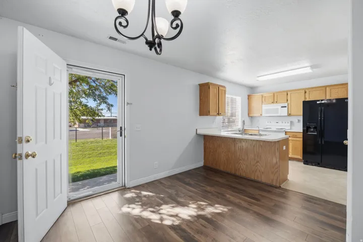 Wood-finish flooring throughout, with a white exterior door leading to green space