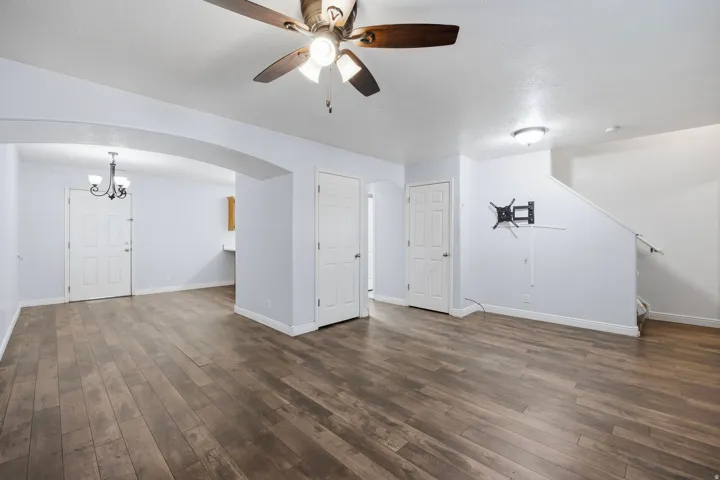 Wood-finish flooring throughout, ceiling fan with integrated lighting, recessed lighting, and an arched entryway