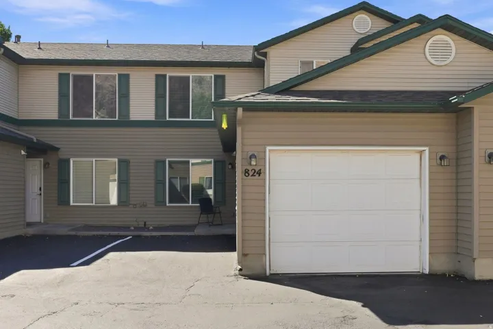 Two-story exterior with horizontal siding, multiple windows with dark shutters, and an attached garage