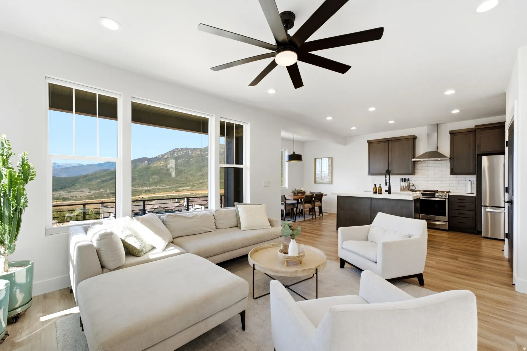 Open-concept living area with wood-finish flooring, recessed lighting, and a contemporary ceiling fan