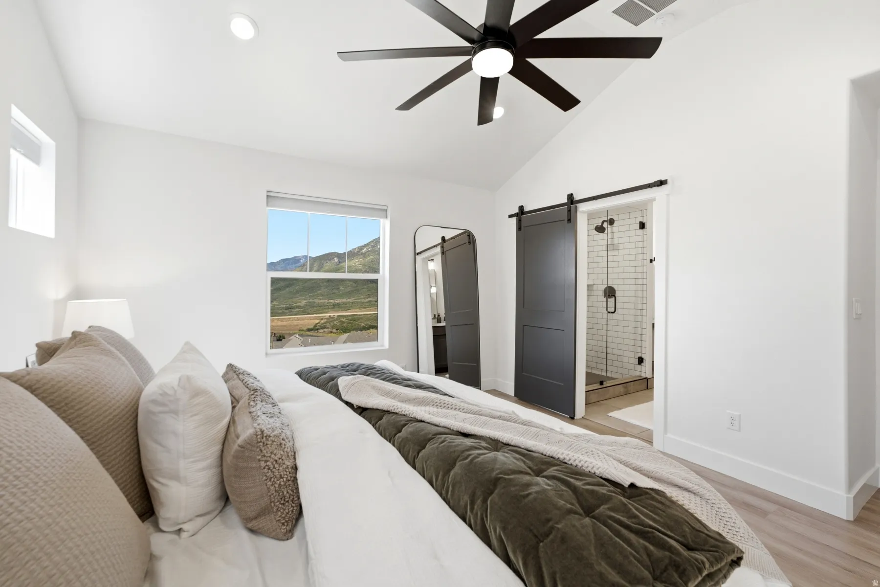 Vaulted ceiling, recessed lighting, ceiling fan, dual windows, and two sliding barn doors