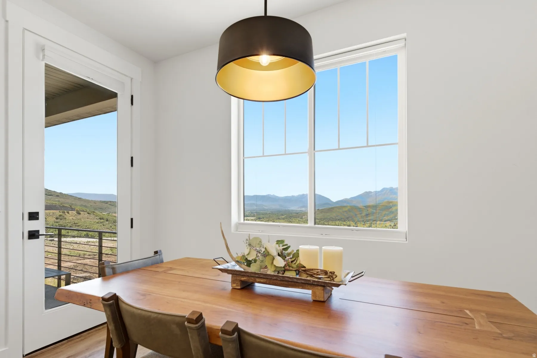 Expansive window with mountain scenery, direct outdoor access, and a dark-toned pendant light fixture