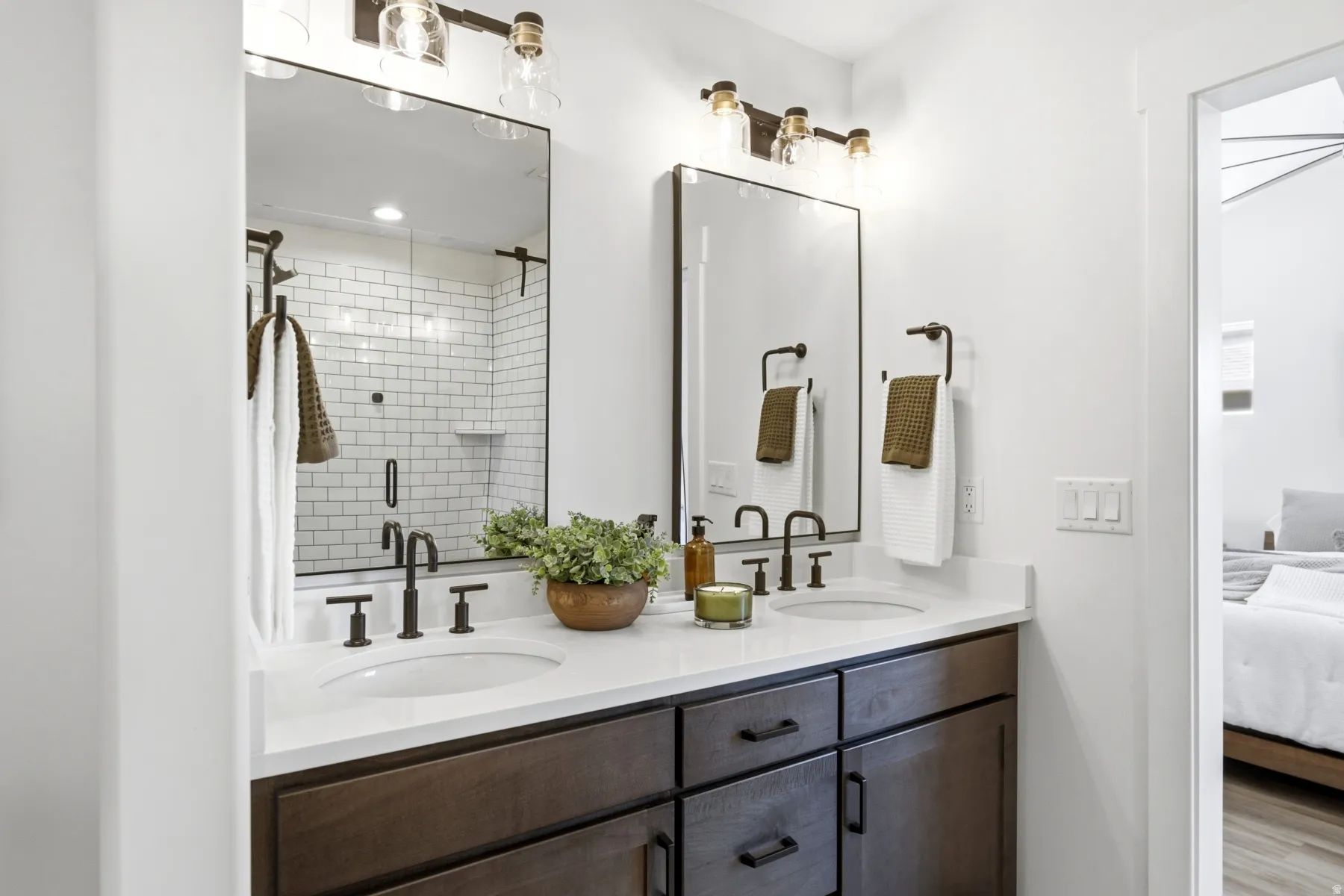 Dual rectangular mirrors, a double vanity with stone-look countertop, wood-finish cabinetry, and matte black fixtures