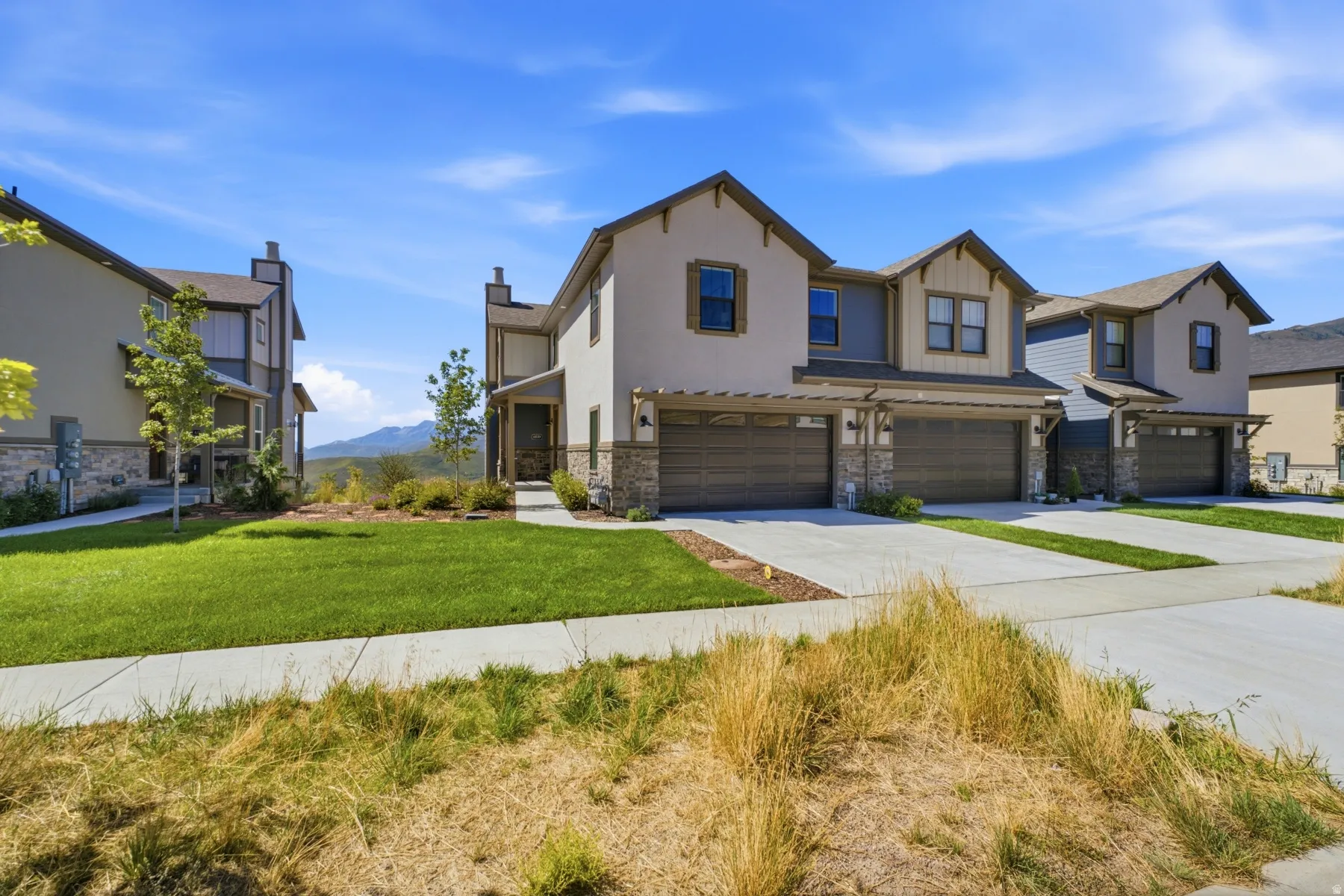 Stucco exterior with stone accents, attached two-car garage, covered entry, and landscaped front yard