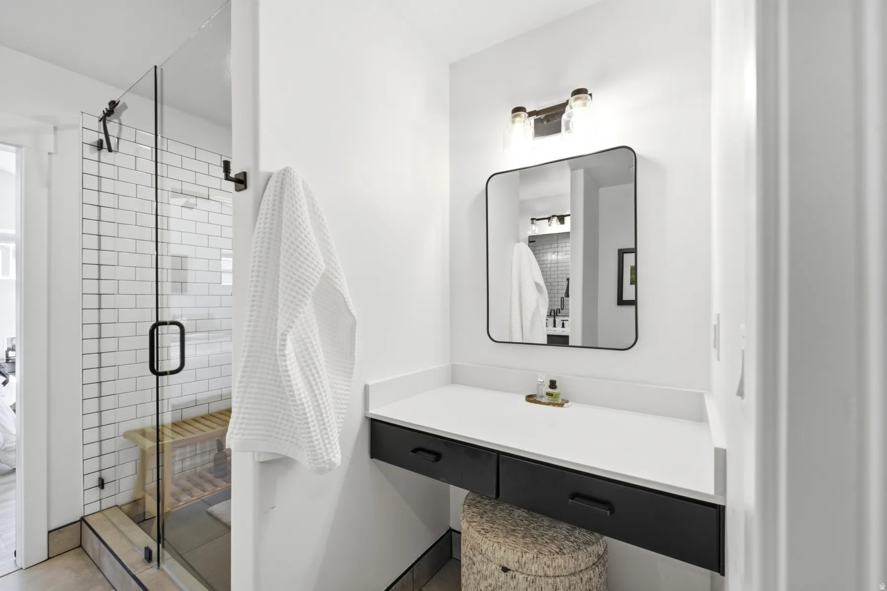 Glass-enclosed shower with subway tile surround and built-in bench