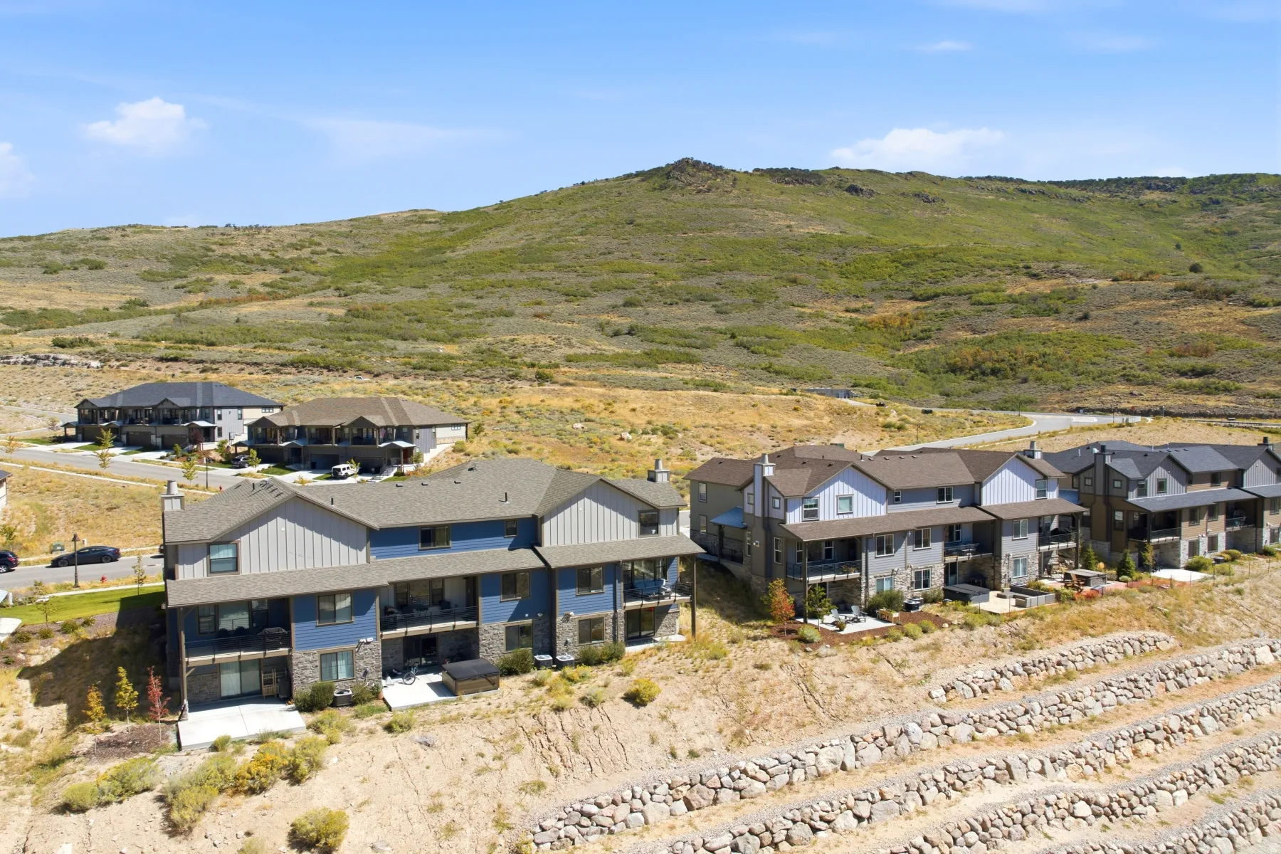 Contemporary multi-story residences featuring balconies, patios, and a stone retaining wall system