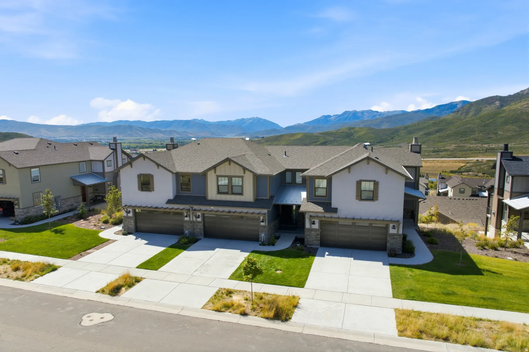 Multi-unit residence featuring a gabled roofline, stone and stucco exterior, and attached garages