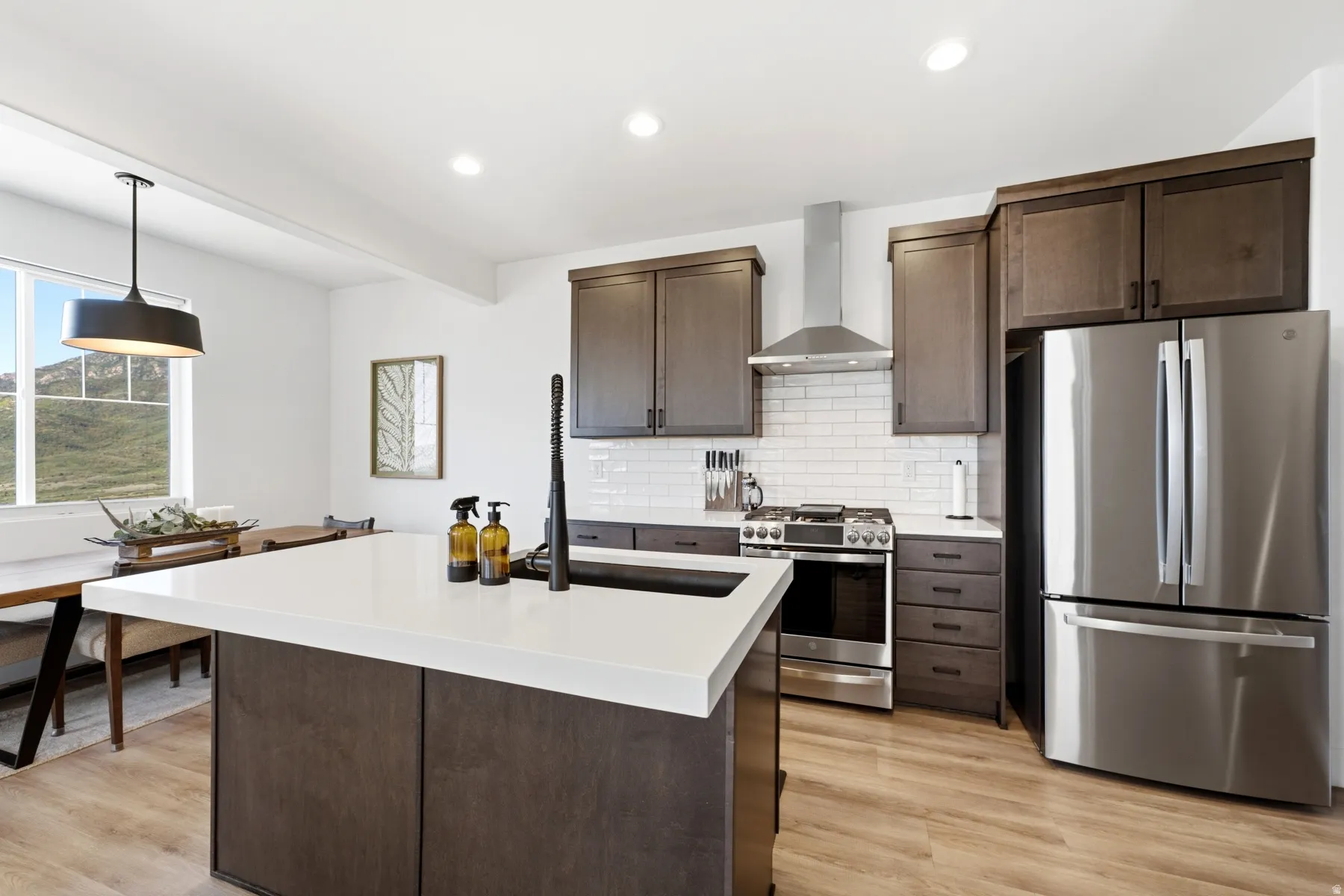 Kitchen featuring a large island with a white countertop, dark wood-finish cabinetry, stainless steel appliances, and a subway tile backsplash