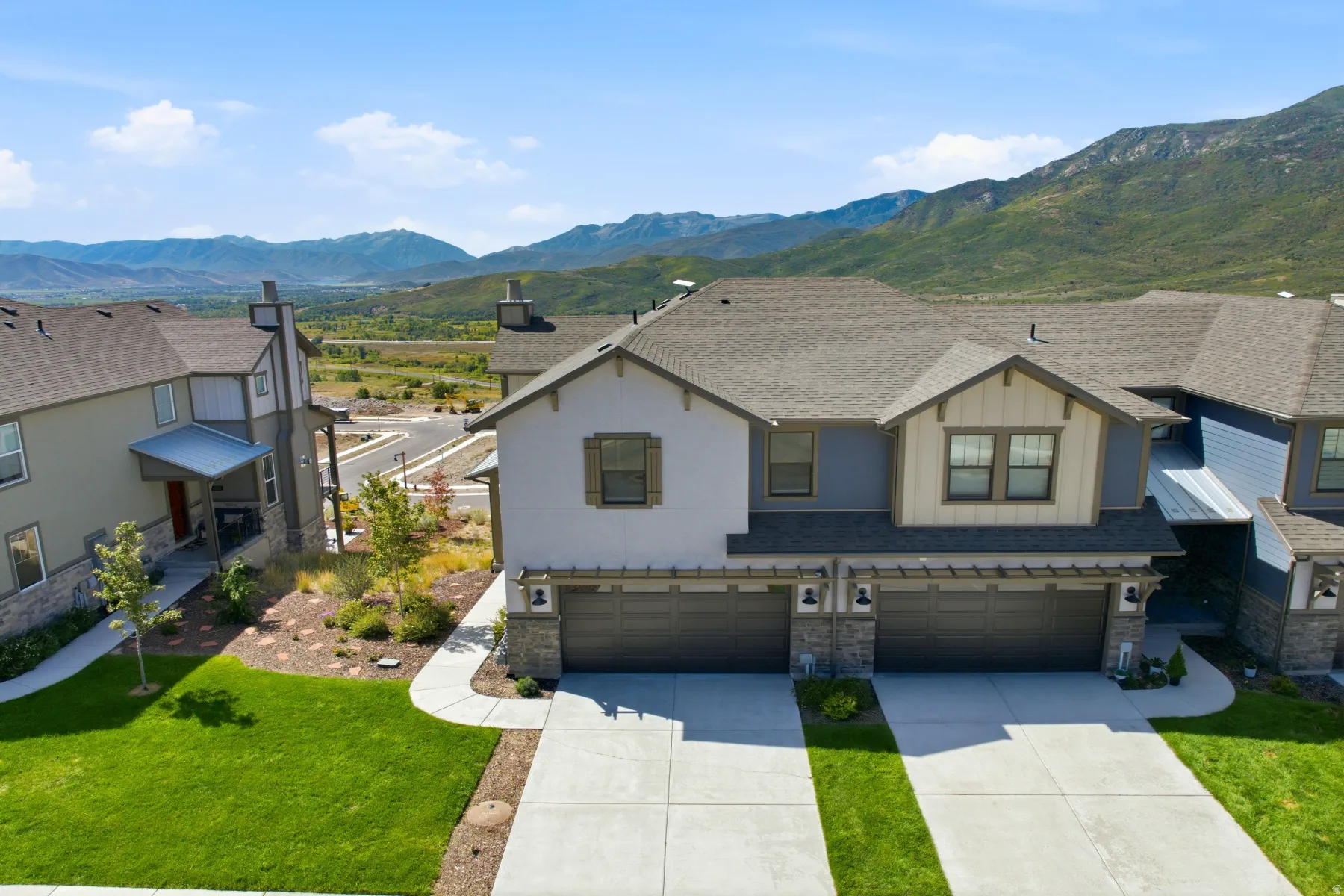Contemporary multi-family residence with an attached two-car garage, stone accents, and a distinctive gable roofline