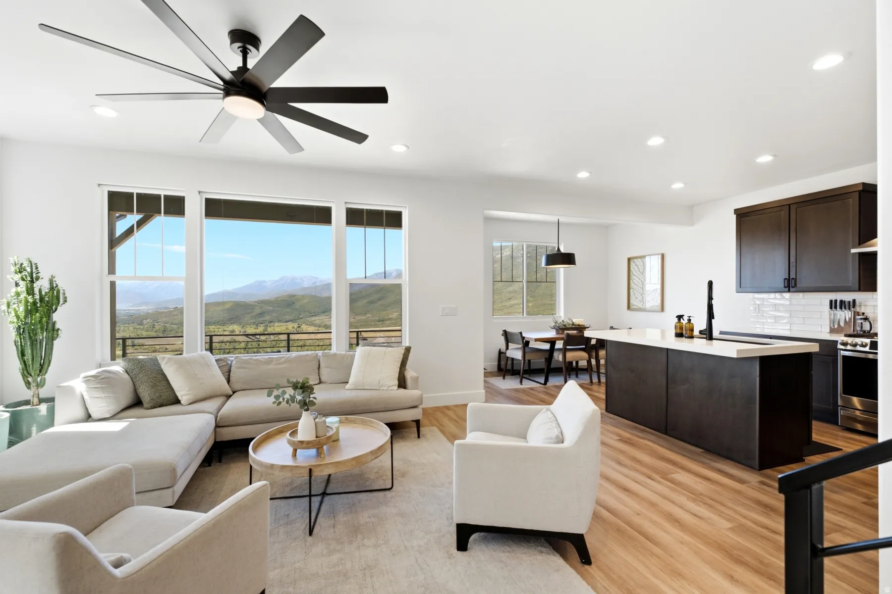 Spacious living area featuring large windows, wood-finish flooring, recessed lighting, and a modern ceiling fan