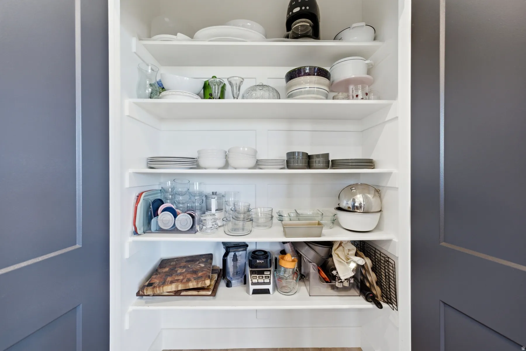 Built-in white shelving system with multiple tiers, set within a recessed alcove