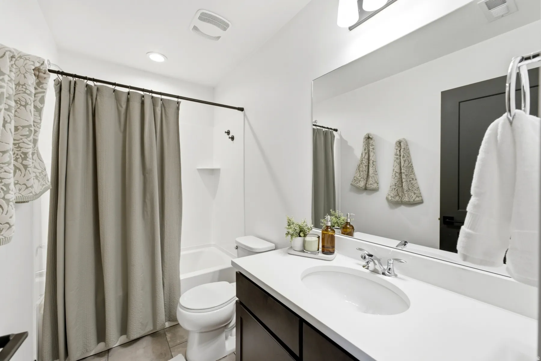 White vanity with integrated sink, chrome faucet, and expansive wall mirror