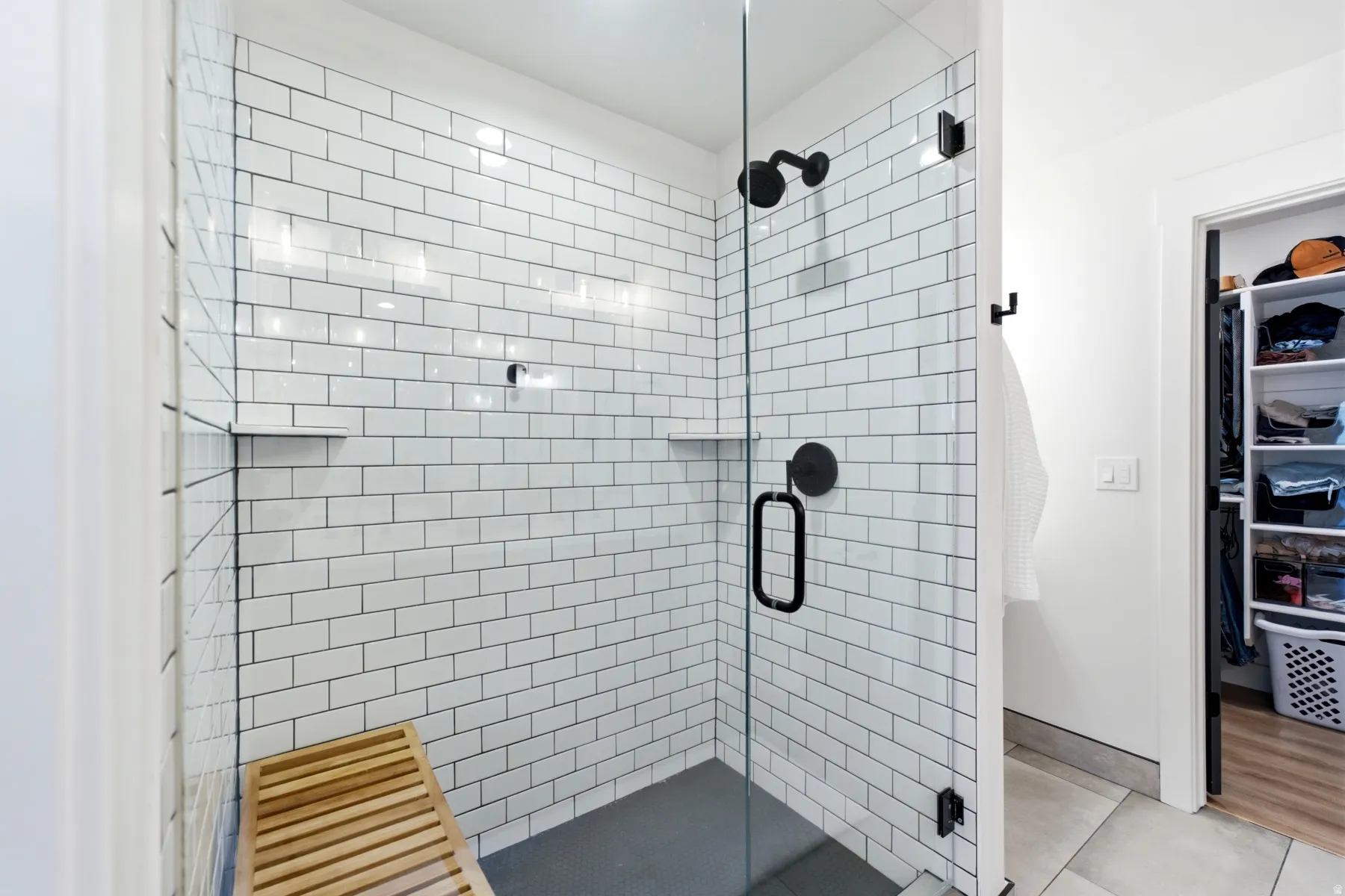 Walk-in shower featuring white subway tile, a dark-toned shower pan, and matte black fixtures