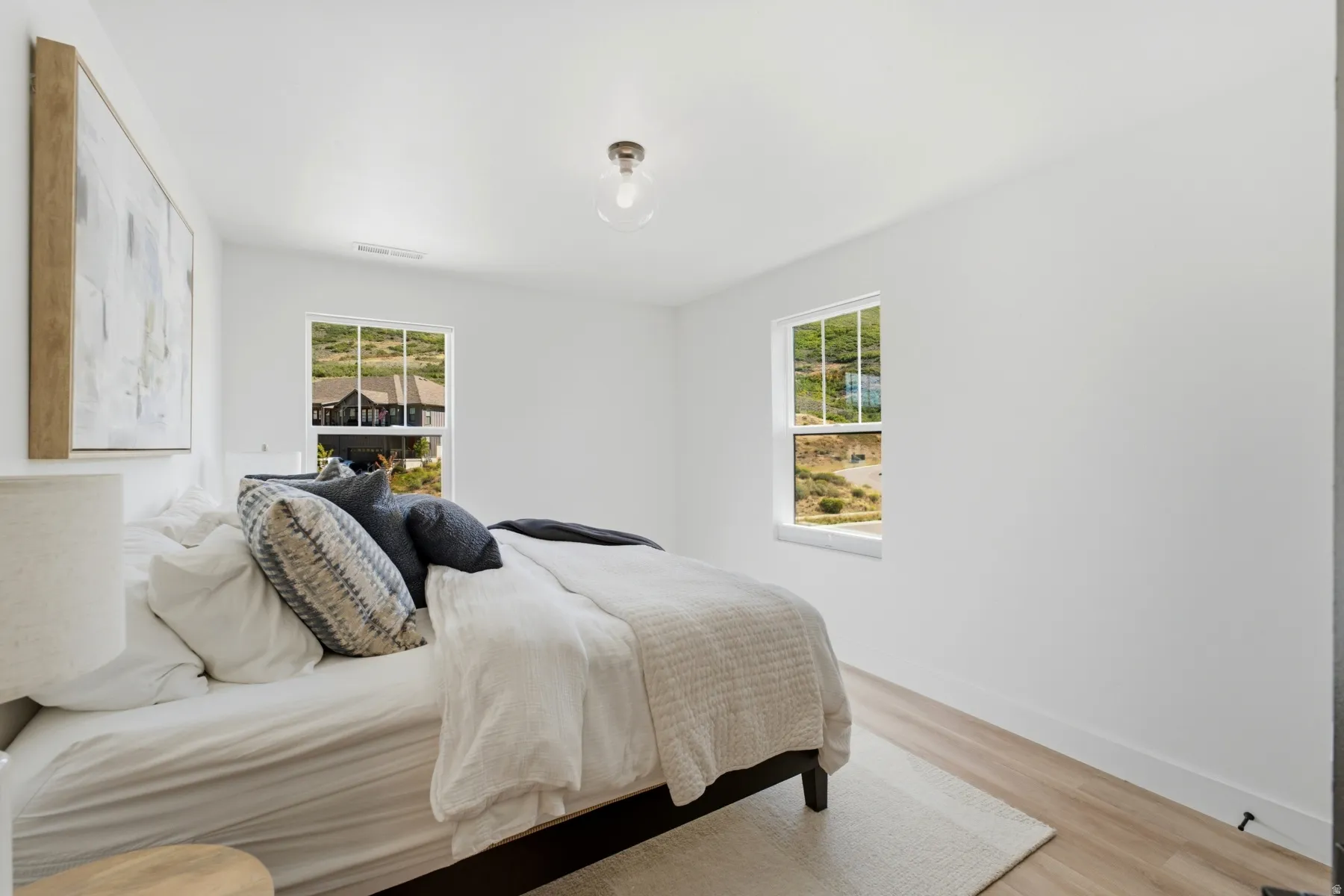 Recessed lighting, wood-finish flooring, two large windows, white walls, and a ceiling-mounted light fixture
