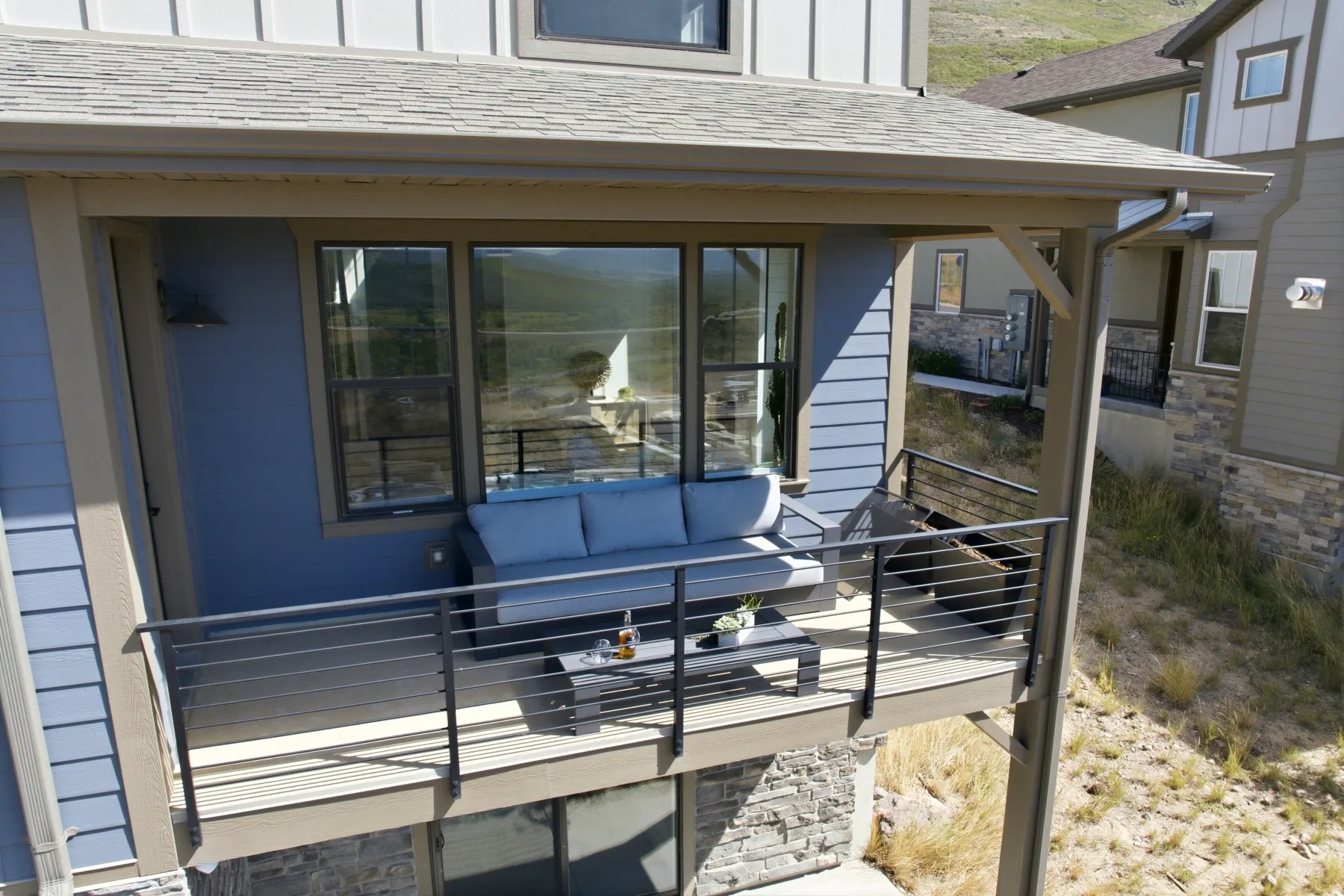 Balcony with cable railing, large windows, exterior wall sconce, and composite decking