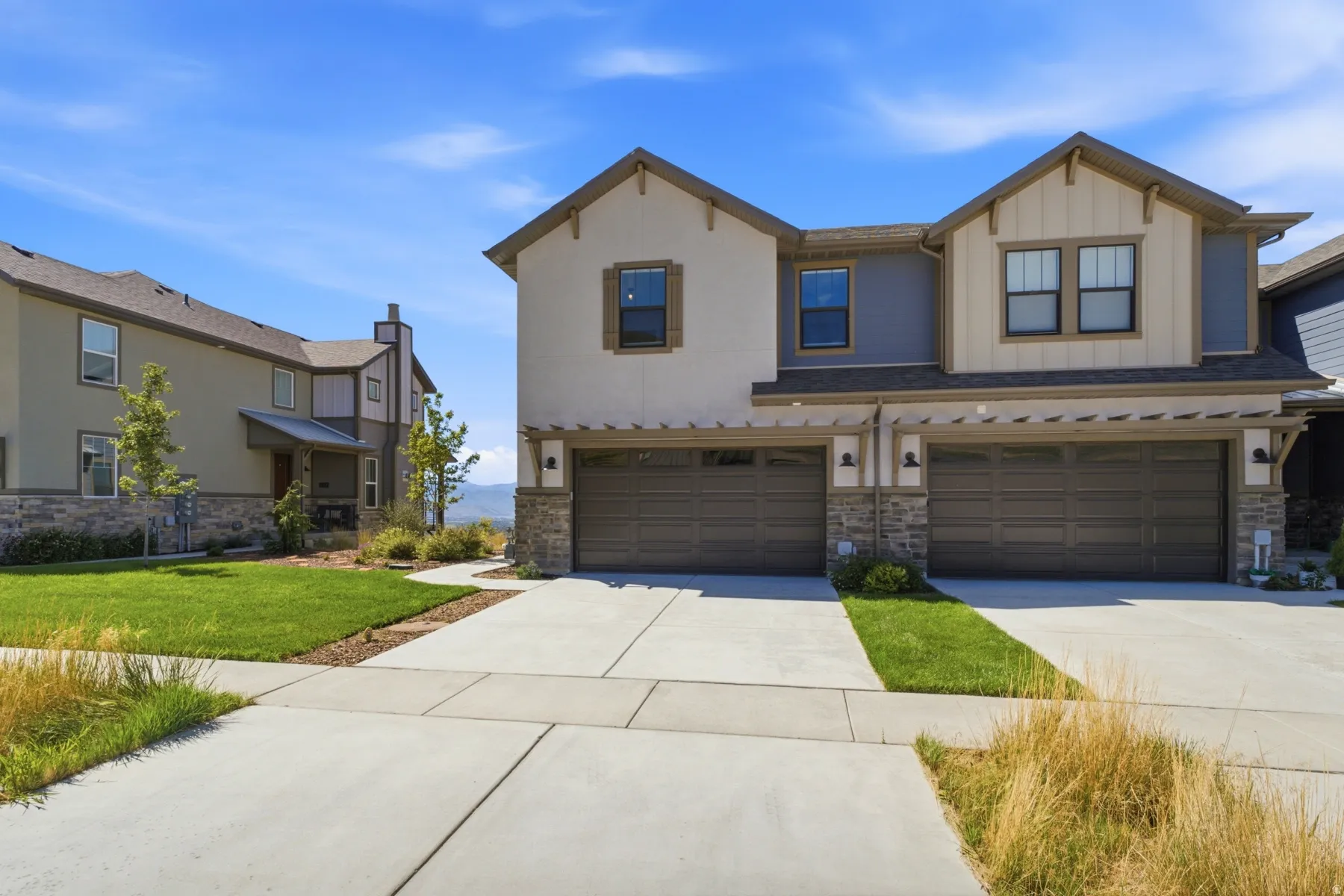 Modern exterior with stone accents, attached two-car garage, and concrete driveway