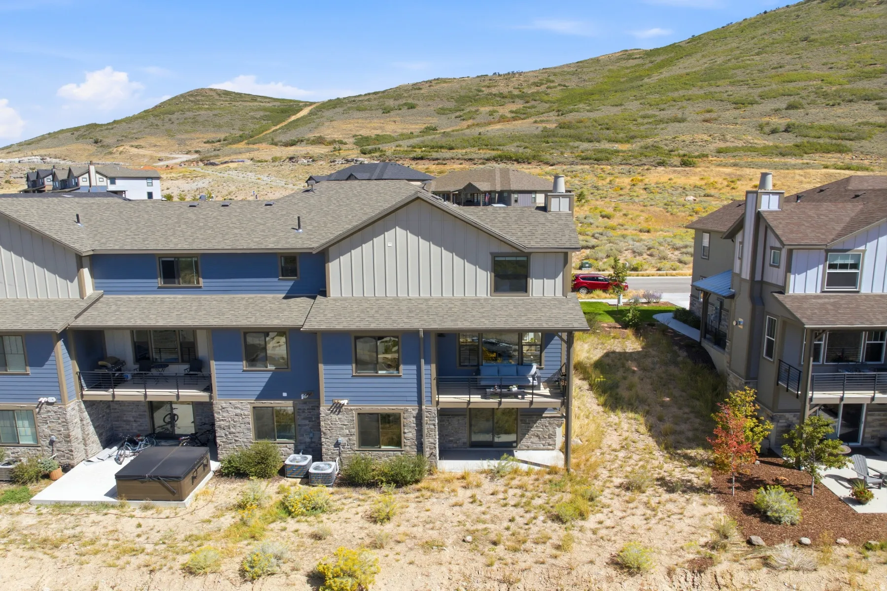 Multi-level townhome featuring a stone and siding exterior, multiple balconies, and a ground-level patio