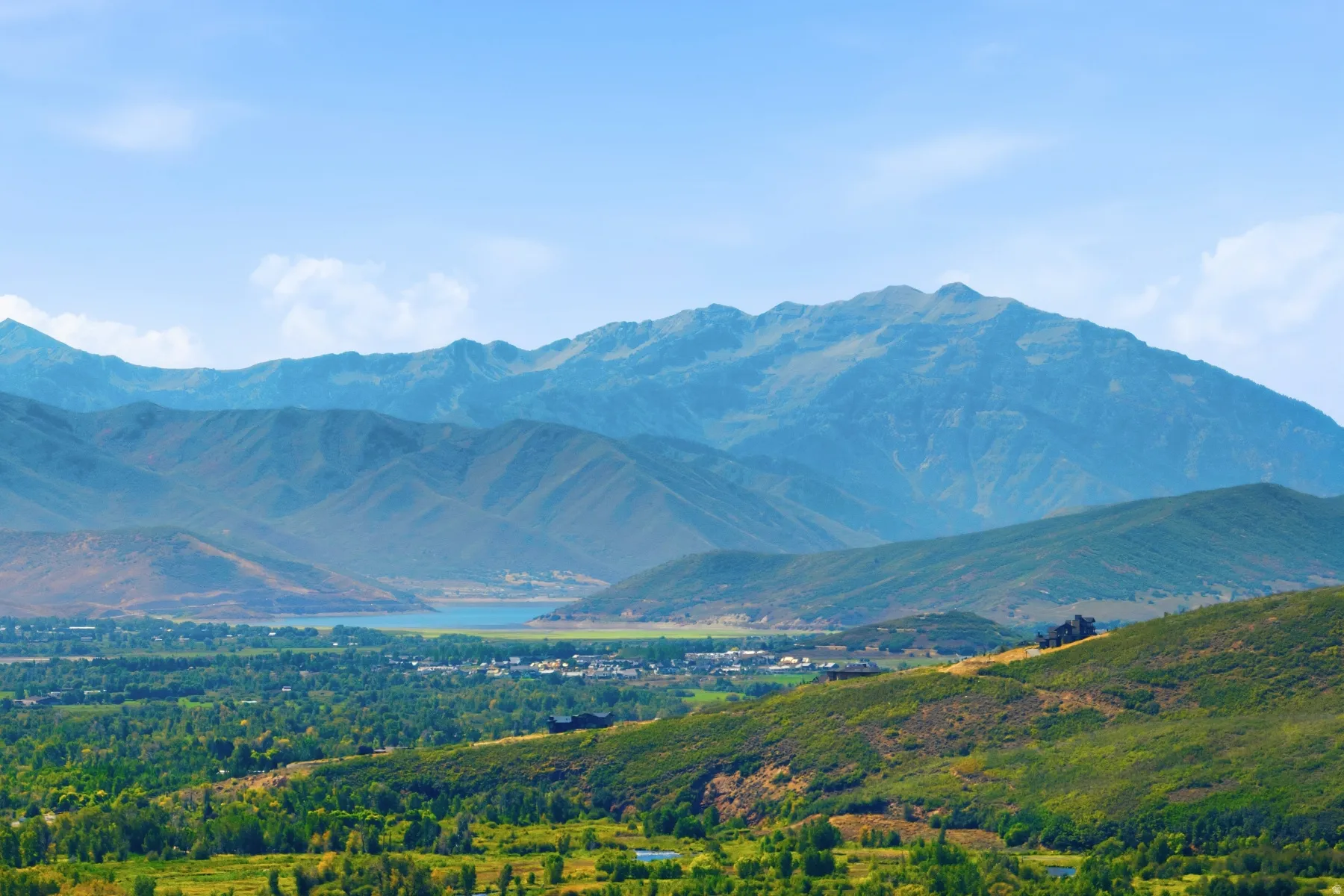 Expansive mountain scenery with distant water feature and lush green foothills