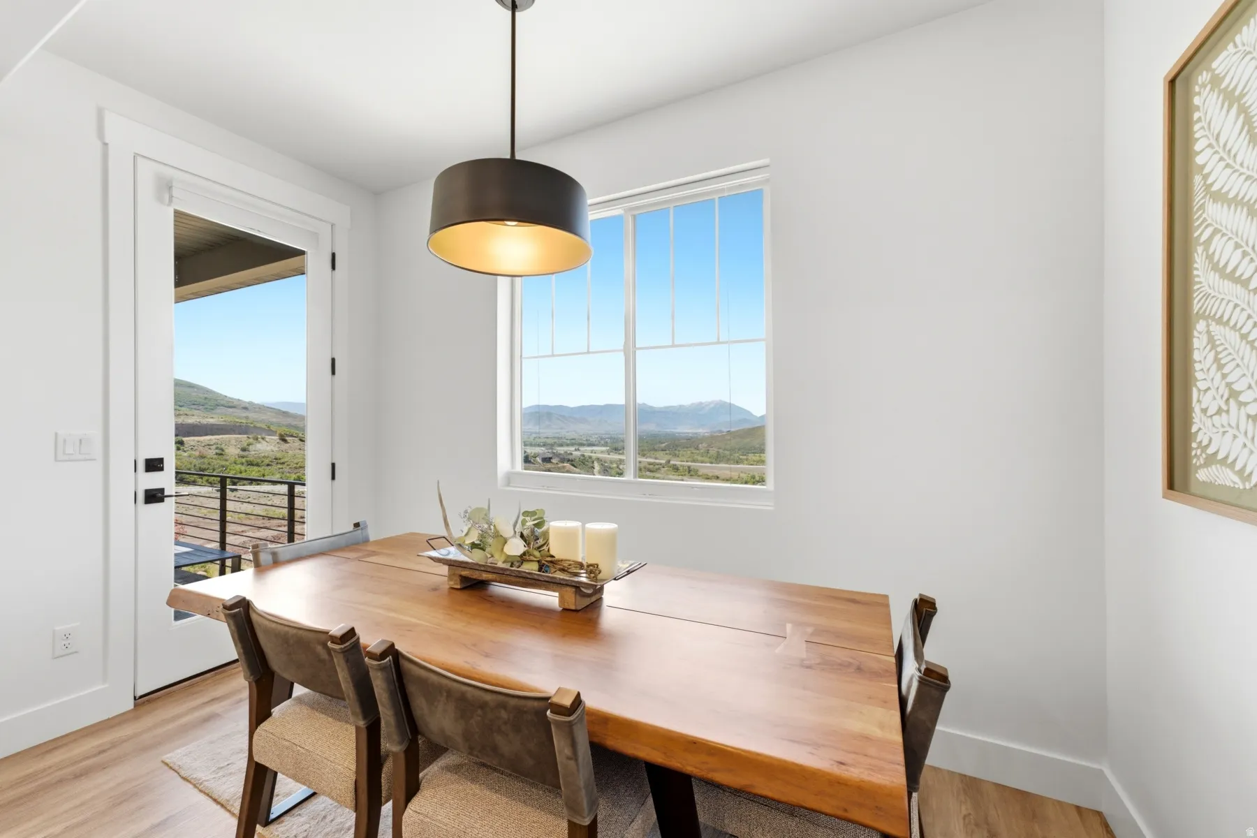 Light-filled dining area featuring wood-finish flooring, a contemporary pendant light fixture, and a glass-paned door leading to an outdoor space