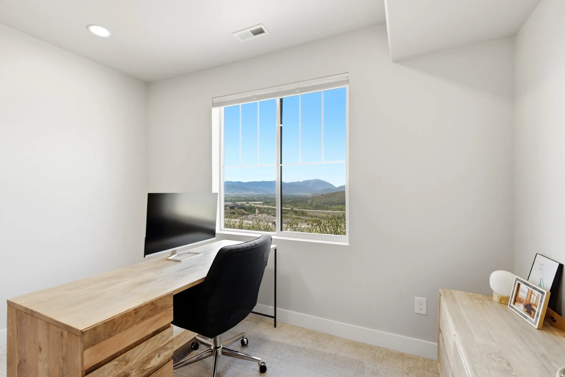 Recessed lighting illuminates a room with a window offering a scenic landscape