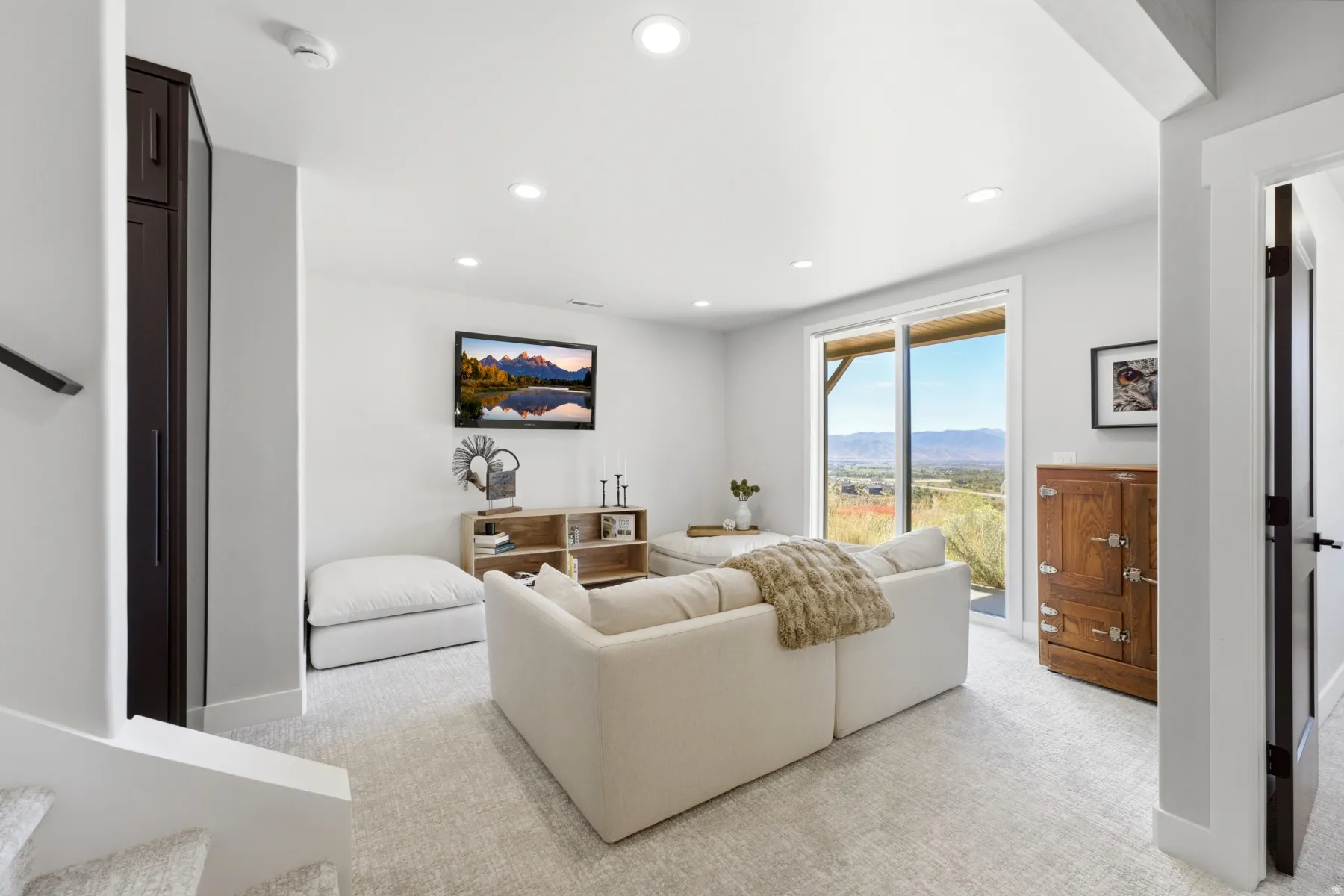 Recessed lighting illuminates this bright space featuring a sliding glass door, dark wood-finish built-in cabinetry, and neutral-toned carpeting