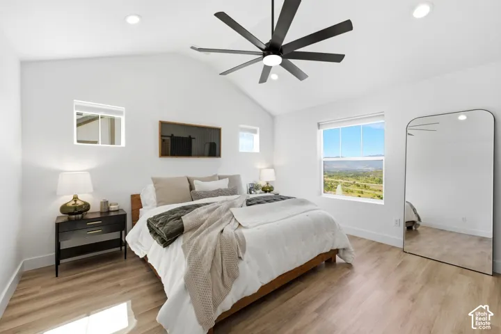 Vaulted ceiling, recessed lighting, wood-finish flooring, large window, and ceiling fan with black blades