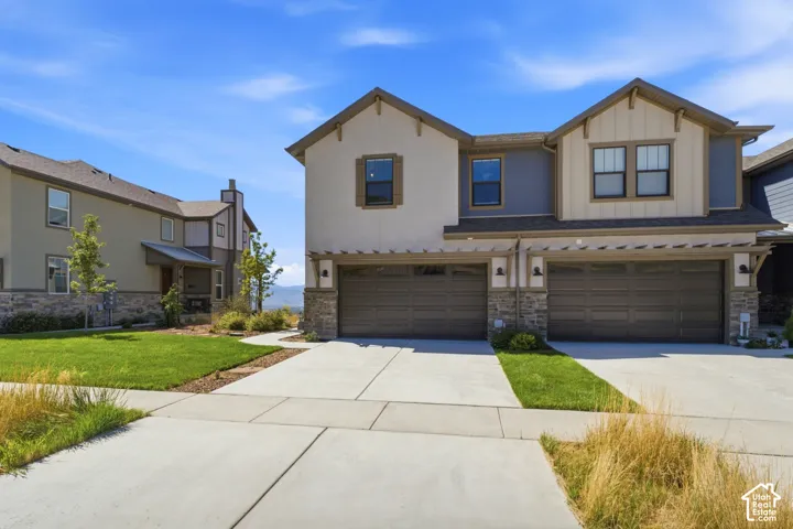 Modern exterior with stone accents, attached two-car garage, and concrete driveway