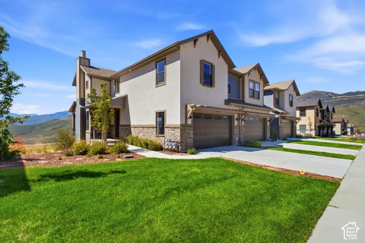 Multi-level residence featuring a stucco and stone veneer exterior, a two-car garage with a pergola, and a concrete driveway