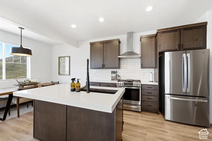 Kitchen featuring a large island with a white countertop, dark wood-finish cabinetry, stainless steel appliances, and a subway tile backsplash