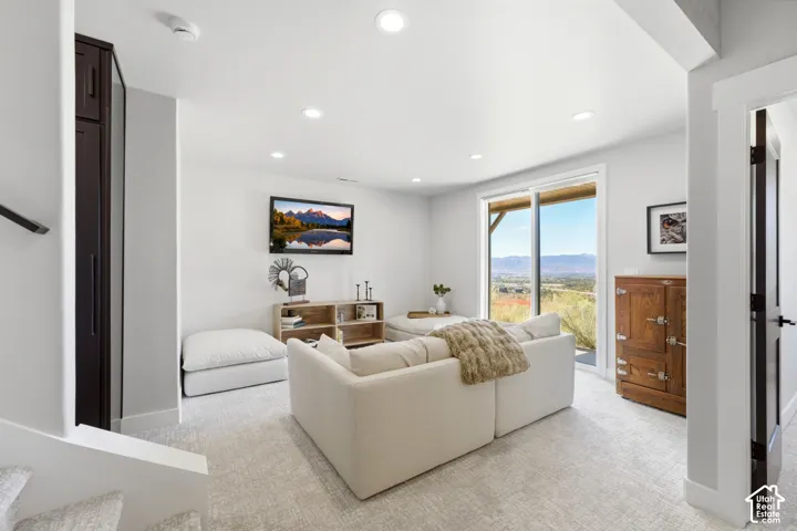 Recessed lighting illuminates this bright space featuring a sliding glass door, dark wood-finish built-in cabinetry, and neutral-toned carpeting