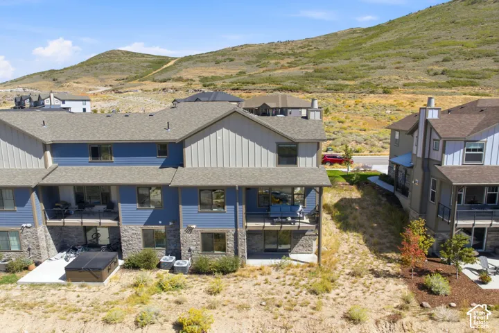 Multi-level townhome featuring a stone and siding exterior, multiple balconies, and a ground-level patio